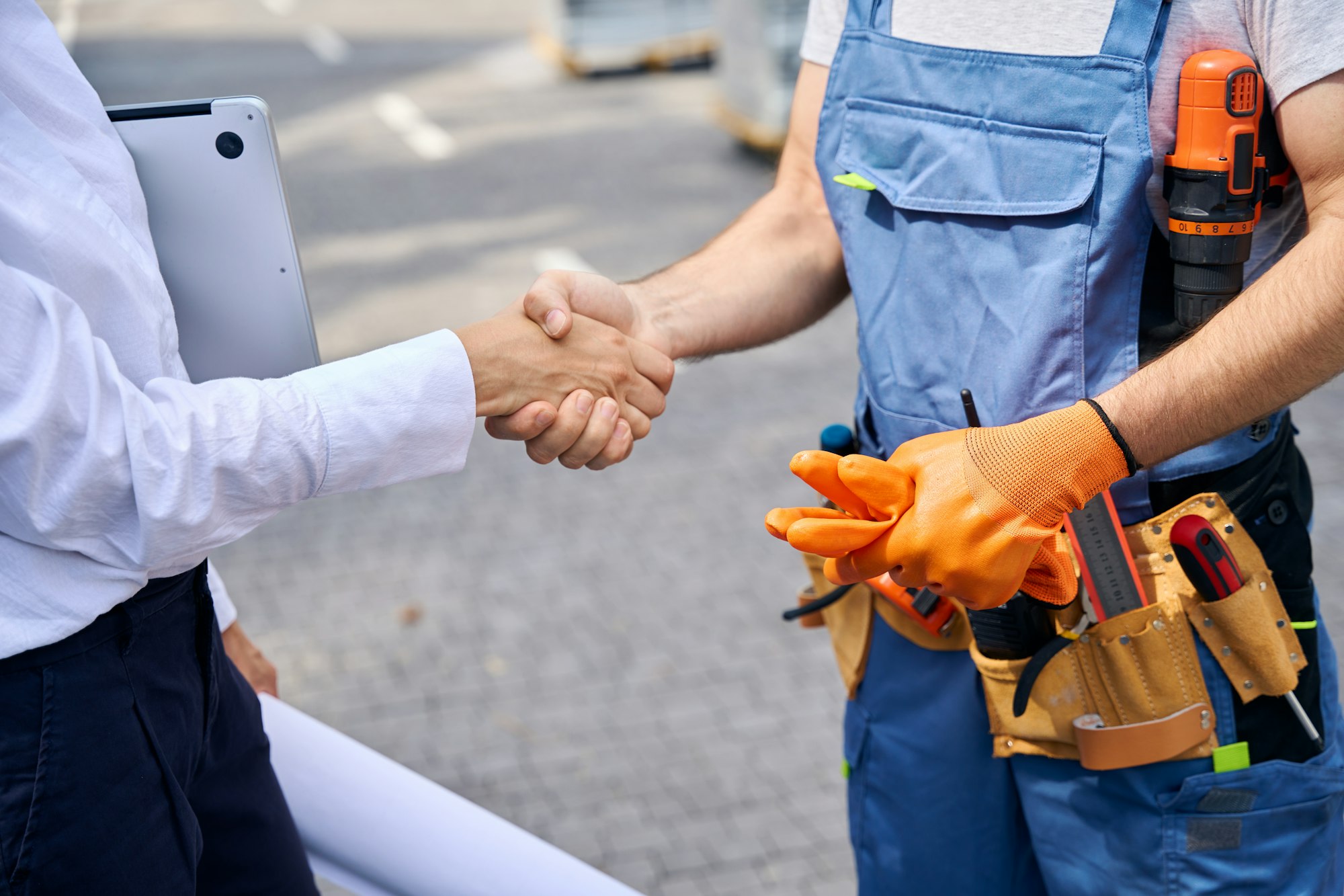 Building inspector and builder greeting each other with handshake outdoors